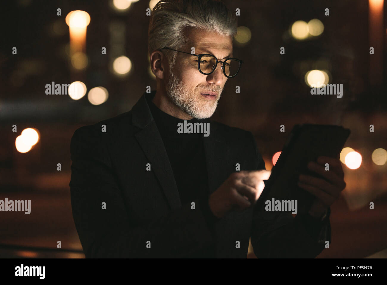 Senior Business Associate arbeiten an Tablet Computer bis spät in die Nacht im Büro. Reifer Mann Überstunden im Büro. Stockfoto