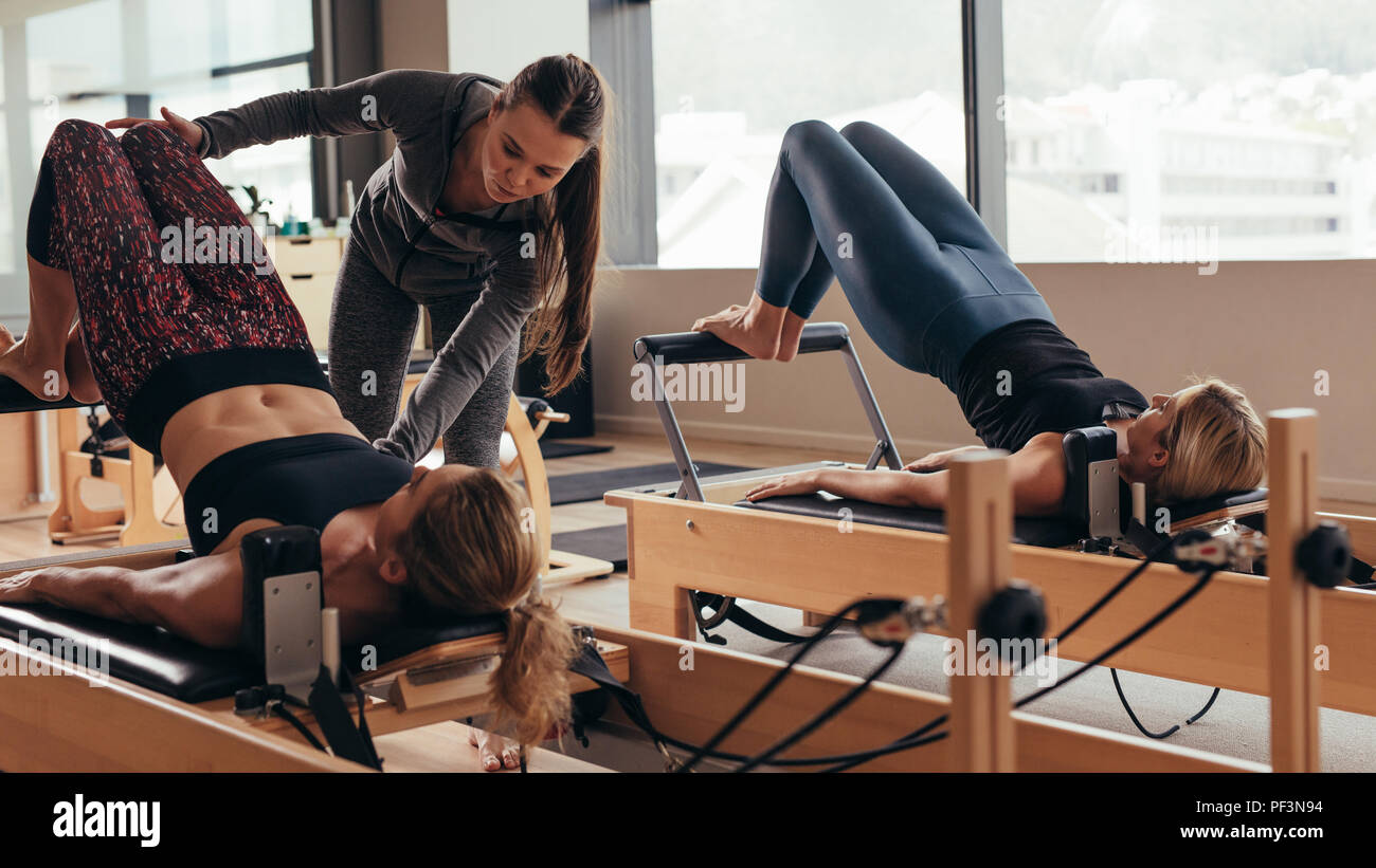 Pilates Instructor Training Frauen an der Turnhalle. Zwei fitness Frauen, Pilates Workout auf Pilates Equipment. Stockfoto