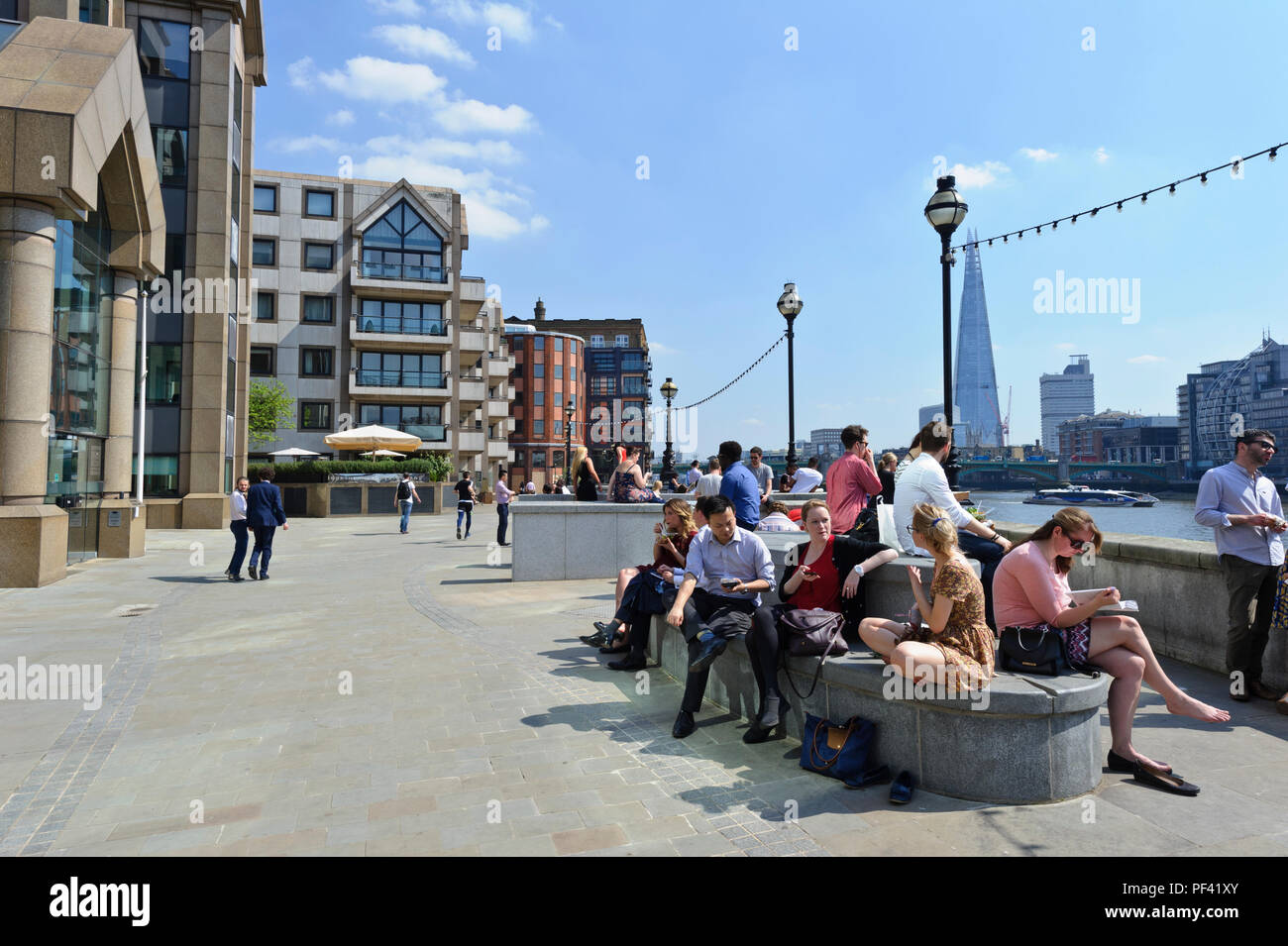 Die Menschen genießen die heißen britisches Wetter entspannen von der Thames River Bank, London, England, Großbritannien Stockfoto