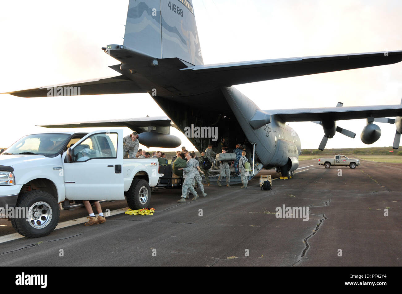 Service für Mitglieder von der US Air National Guard und Navy Reserve Ausrüstung aus einer C-130 Hercules entladen nach der Ankunft in Molokai, Hi, 10.08.2018 zu Tropic Care Maui County 2018. Tropic Care Maui County 2018 ist eine gemeinsame, "hands-on"-Readiness Training Mission, die keine Kosten für medizinische, zahnmedizinische und Vision Dienstleistungen für die Menschen an sechs Standorten in Maui, Molokai und Lanai von August 11-19. (U.S. Air National Guard Foto: Staff Sgt. Lonnie Wiram) Stockfoto