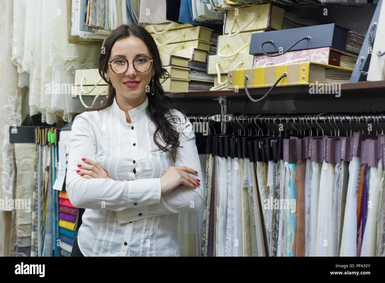 Portrait von Frau Eigentümer mit verschränkten Armen in Dekostoffe store, Hintergrund Stoff Proben. Small Business home Textil shop Stockfoto