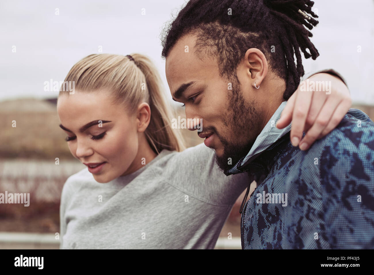 Junge Frau in Sportkleidung stehen mit ihren Arm um ihren Freund während einer Pause von einem Outdoor laufen zusammen Stockfoto
