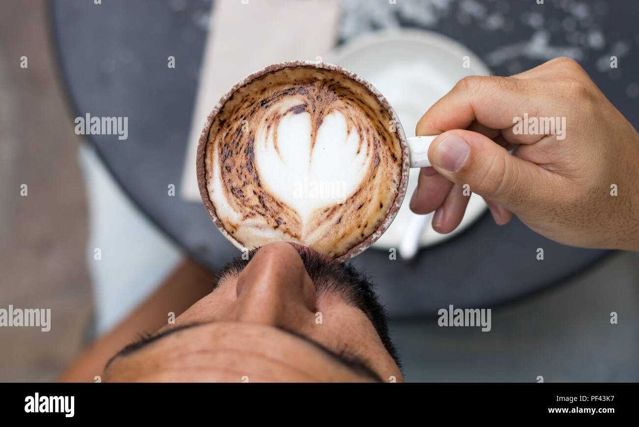 Nahaufnahme von einem Mann trinken einen Cappuccino sitzen draußen in einem Café, die Aussicht von oben. Stockfoto