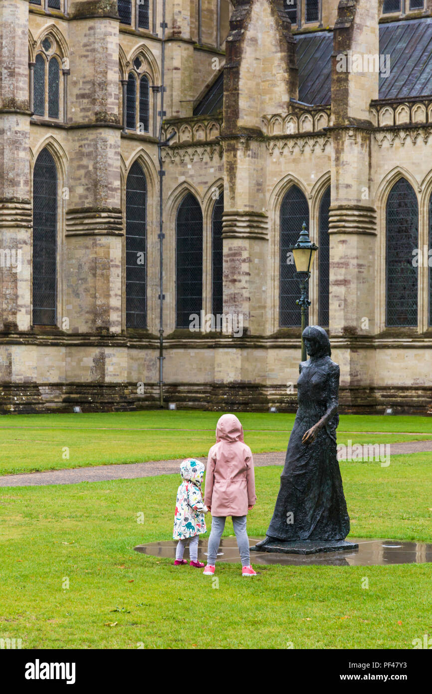 Zwei junge Mädchen mit Blick auf die wenige Madonna Statue und die Lampe vor der Kathedrale von Salisbury in Salisbury, Wiltshire GROSSBRITANNIEN auf einem nassen regnerischen Tag im August Stockfoto