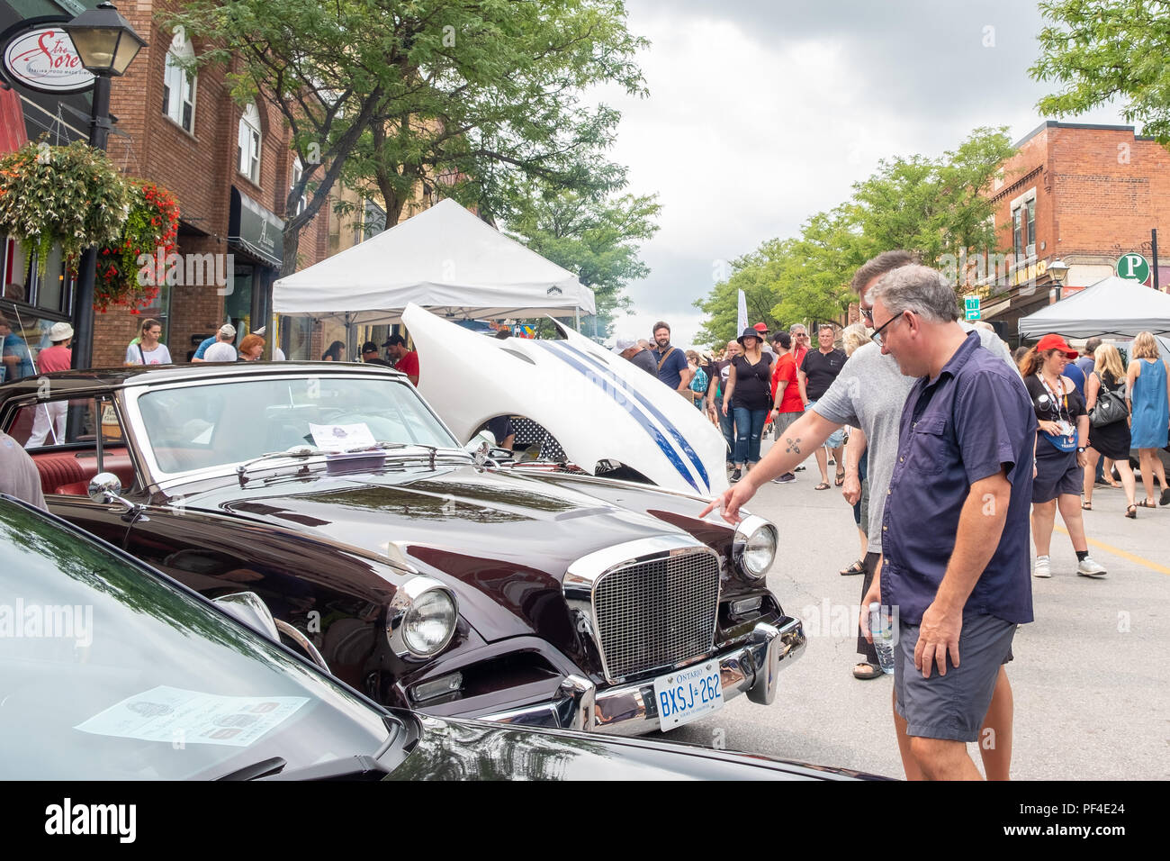 Zwei Männer prüfen und Diskutieren einer der Oldtimer, die auf der jährlichen Downtown Orillia Auto zeigen. Stockfoto