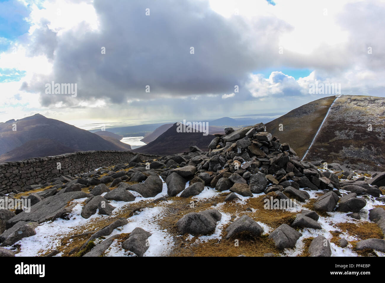 Slieve Meelmore Gipfel Cairn mit leichtem Schneefall. Doan moutain und Silent Valley Reservoir in der Entfernung. Mourne Mountains, N. Irland. Stockfoto