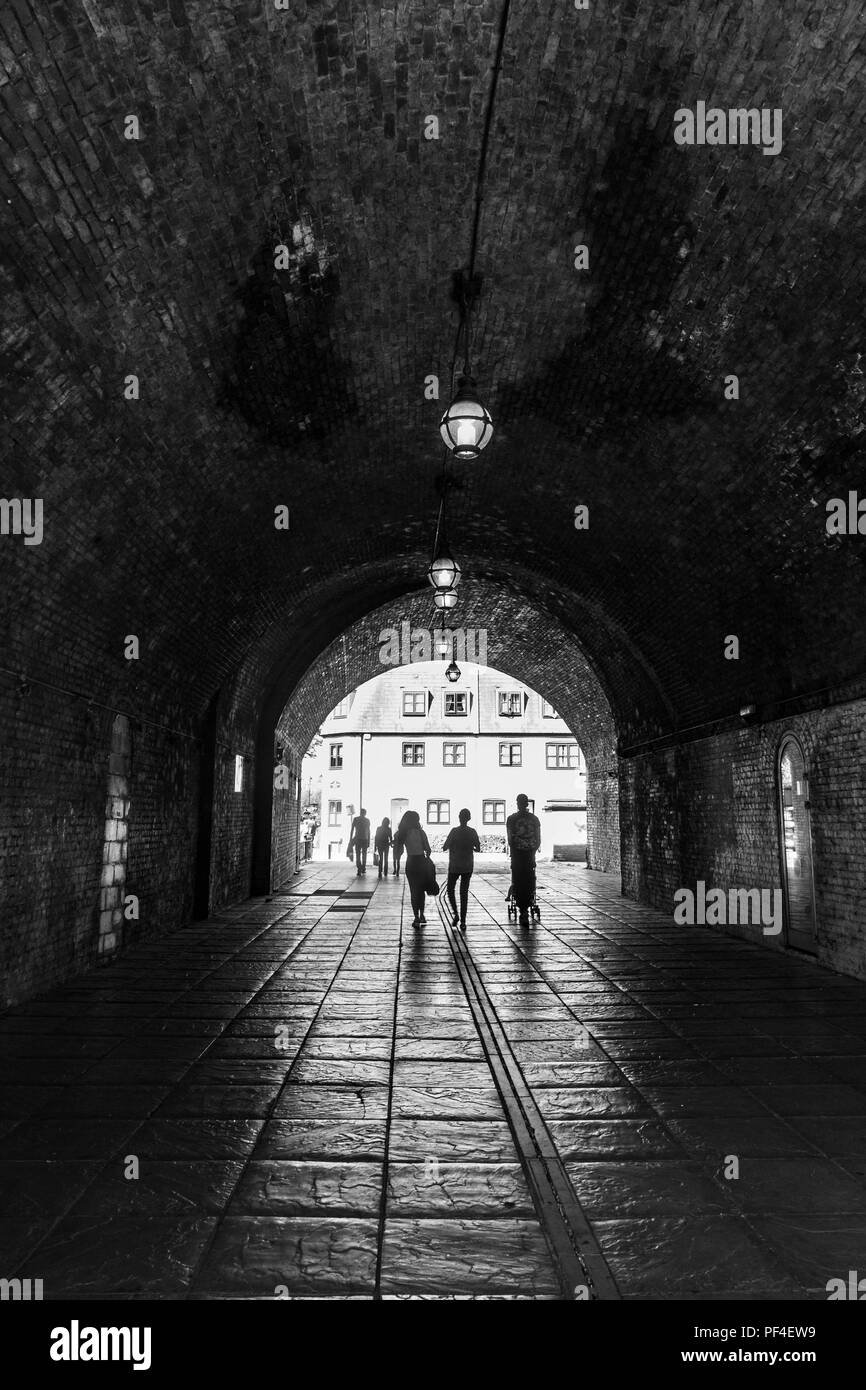 Eine Familie zu Fuß durch einen dunklen Tunnel in Richtung Licht am anderen Ende. Stockfoto
