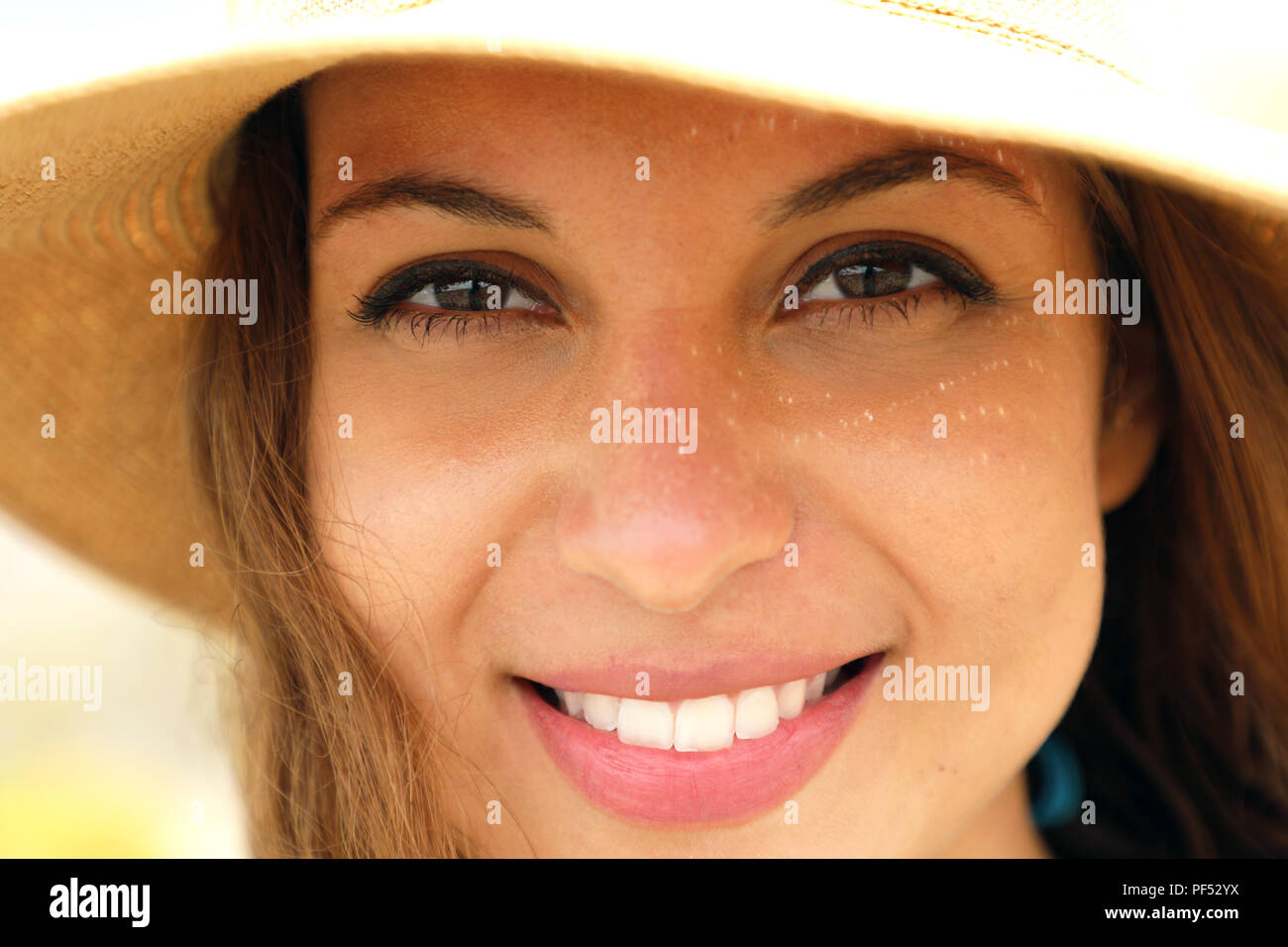 Extreme Nahaufnahme der junge Modell Gesicht mit Stroh Hut lächelnd an Kamera unter Sommer strahlen Sonne am Strand. Sehr in der Nähe von fotogen Modell für Tannin Stockfoto