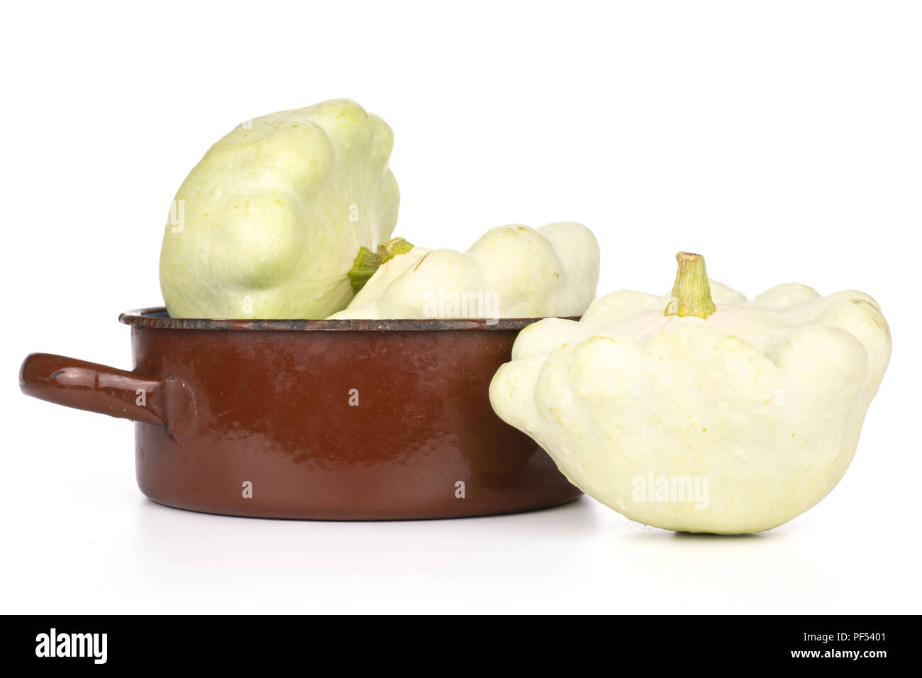 Gruppe von drei ganzen Sommer weiß pattypan Squash in einer gusseisernen Pfanne braun auf weißem Hintergrund Stockfoto
