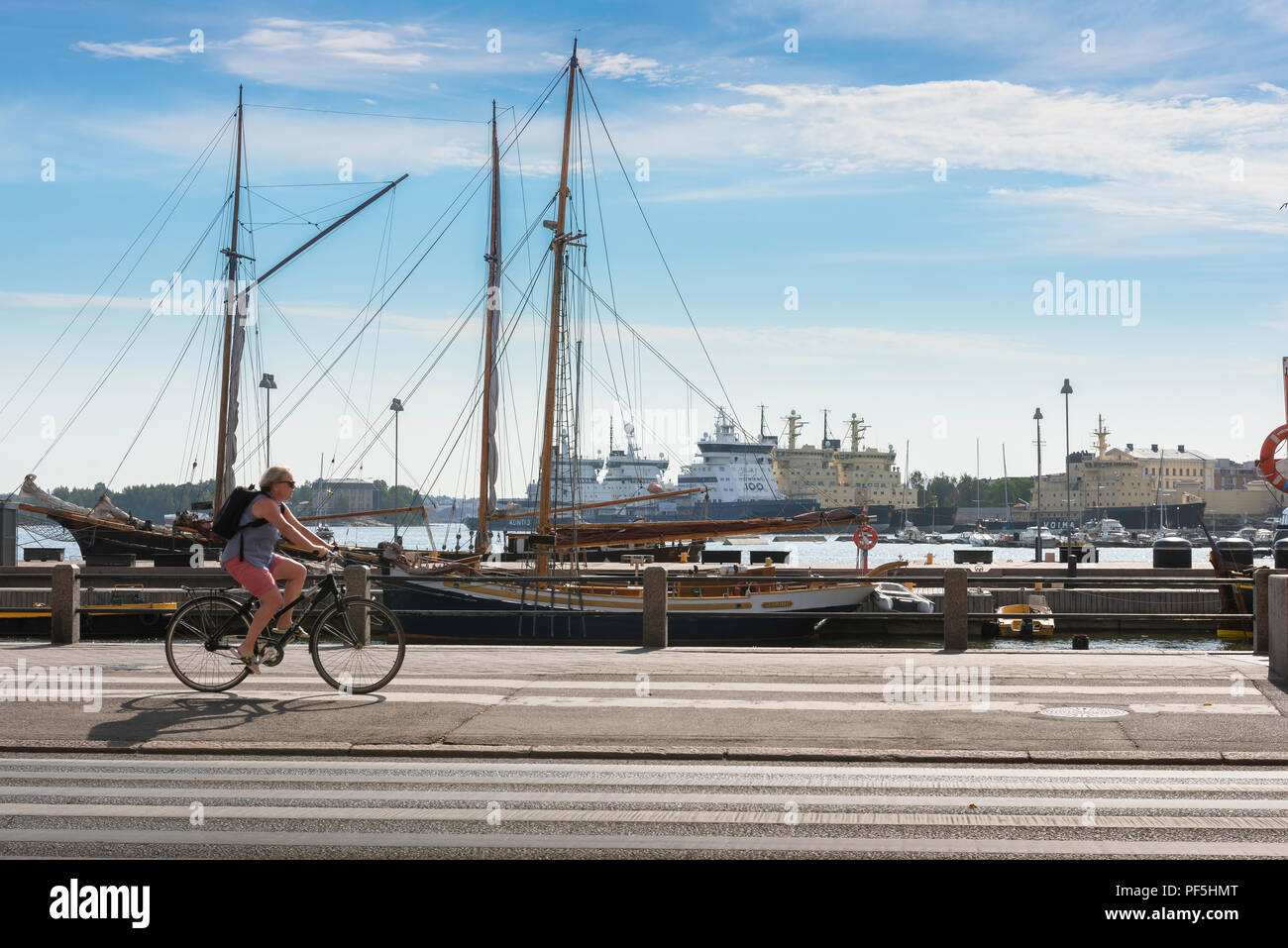 Finnland Radfahren im Sommer, Blick auf eine Frau, die mit dem Fahrrad entlang der Hafen in der Stadt Helsinki an einem Sommermorgen, Finnland. Stockfoto