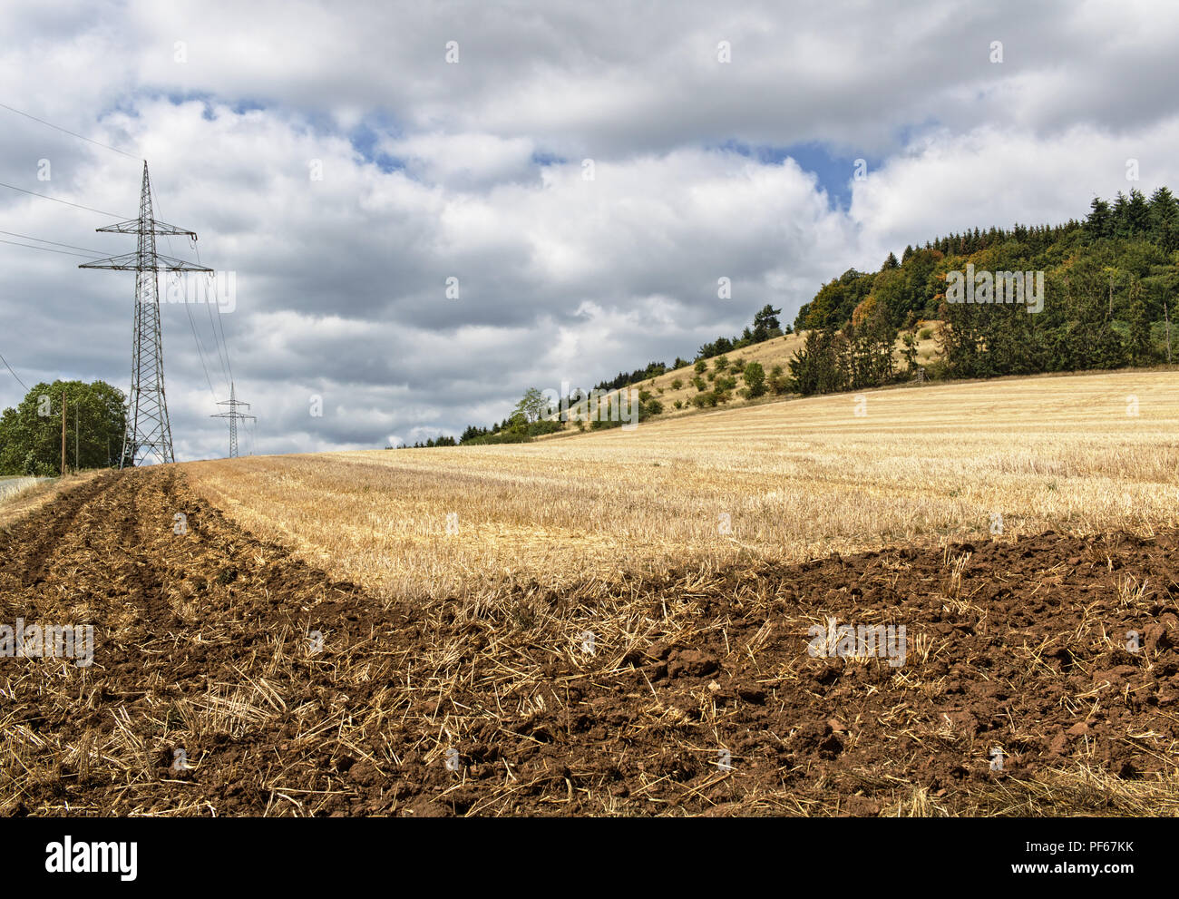 Teilweise Feld nach der Ernte mit Getriebe Turm gepflügt und bewaldeten Hügel im Hintergrund Stockfoto