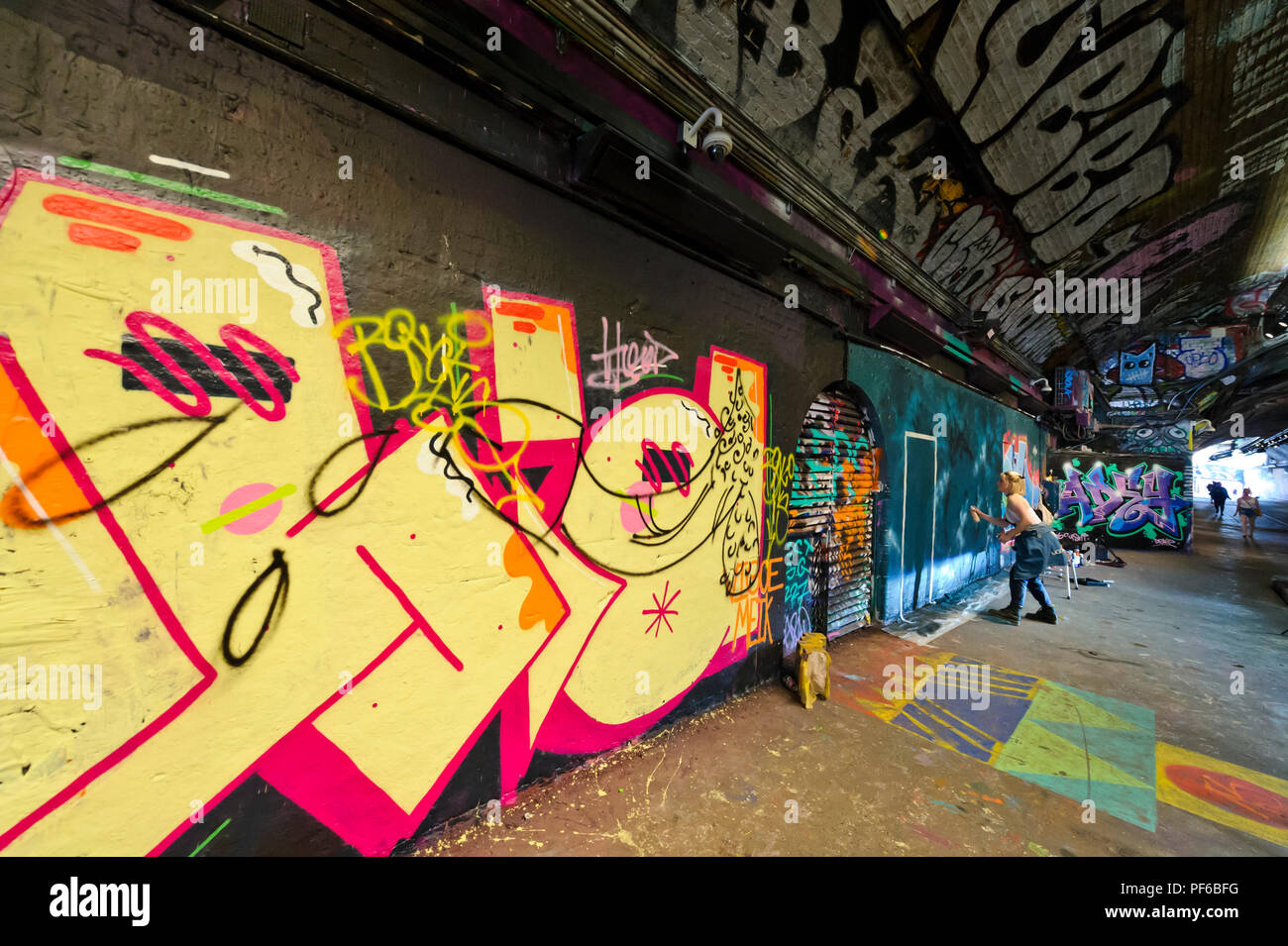 Ein Künstler Farbe spritzen auf der Wand, die in einem Tunnel in London, London, England, Großbritannien Stockfoto