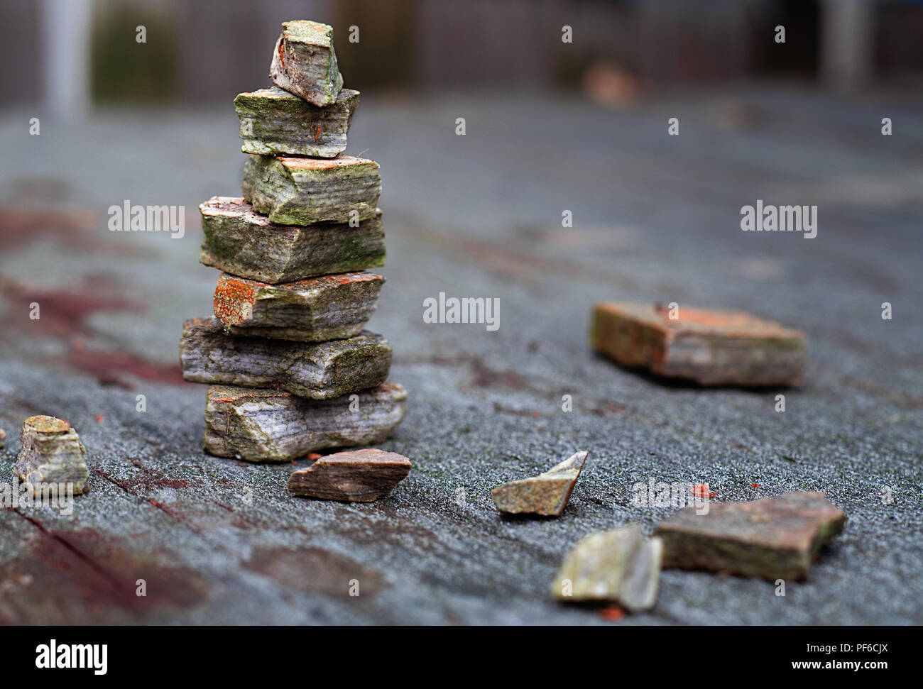 Ein Stapel von alten Steinen in Moos und Rost sitzen auf einem alten Holztisch im Regen abgedeckt Stockfoto