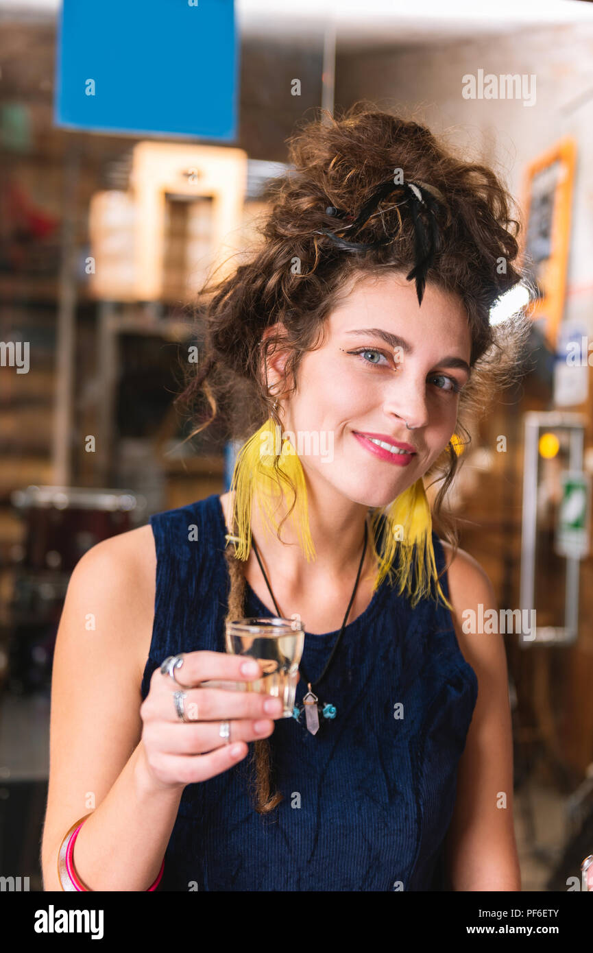 Hippie Frau mit roten Lippen, die Alkohol trinken, sitzen in bar Stockfoto