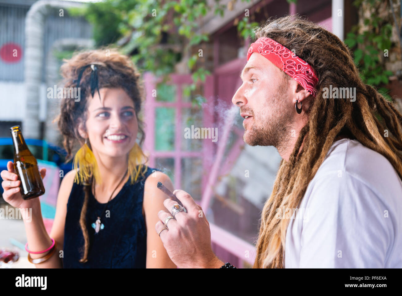 Hippie Mann rauchen Zigarre, während seine Freundin Bier trinken. Stockfoto