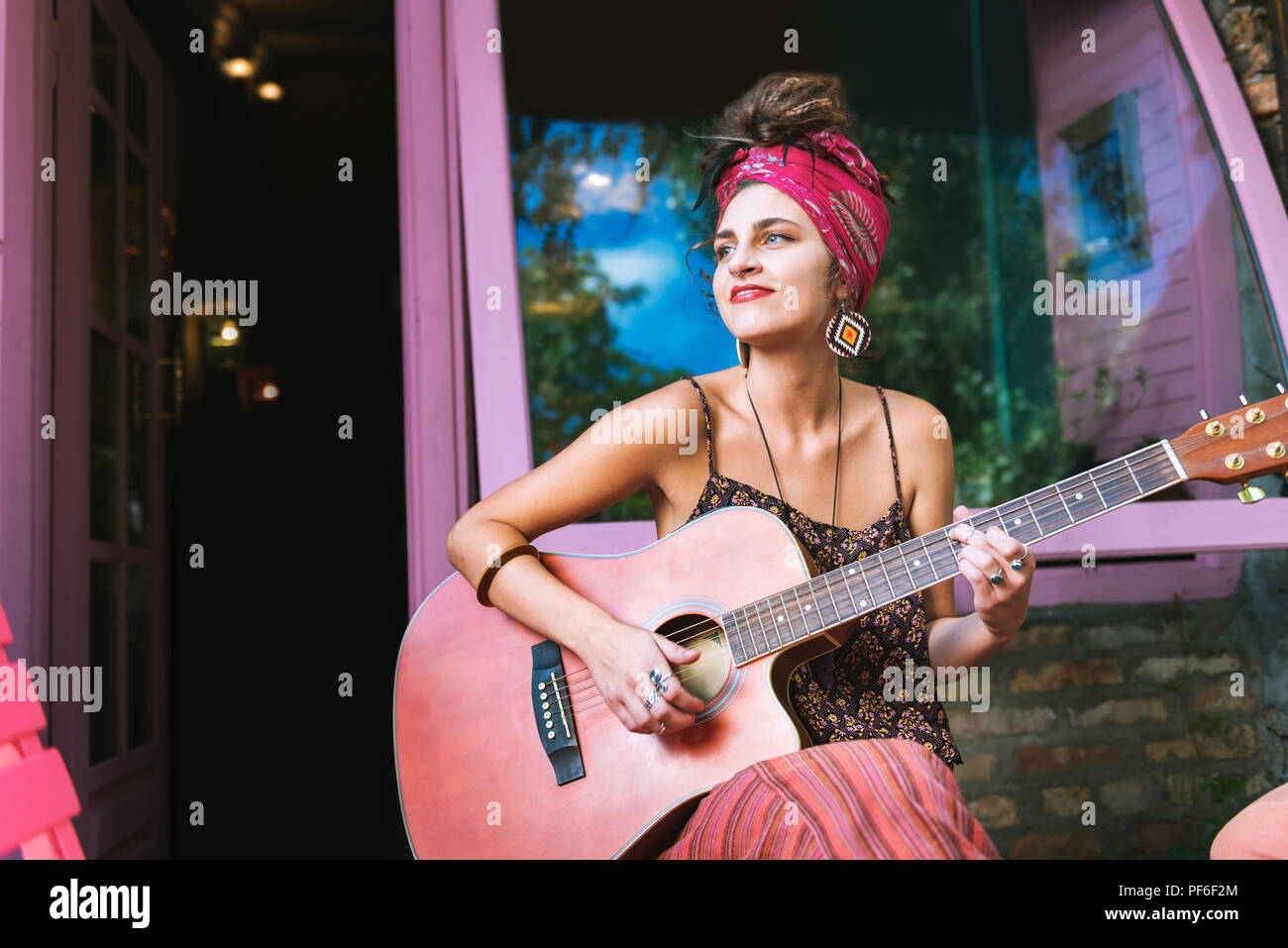 Frau Helle Ohrringe spielen auf der Gitarre outside cafe Stockfoto