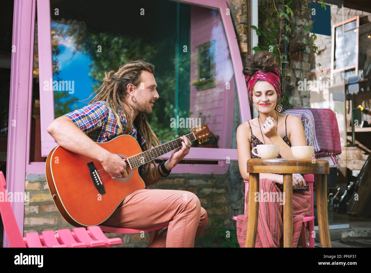 Hippie Mann spielt auf der Gitarre für seine Freundin inspiriert Stockfoto