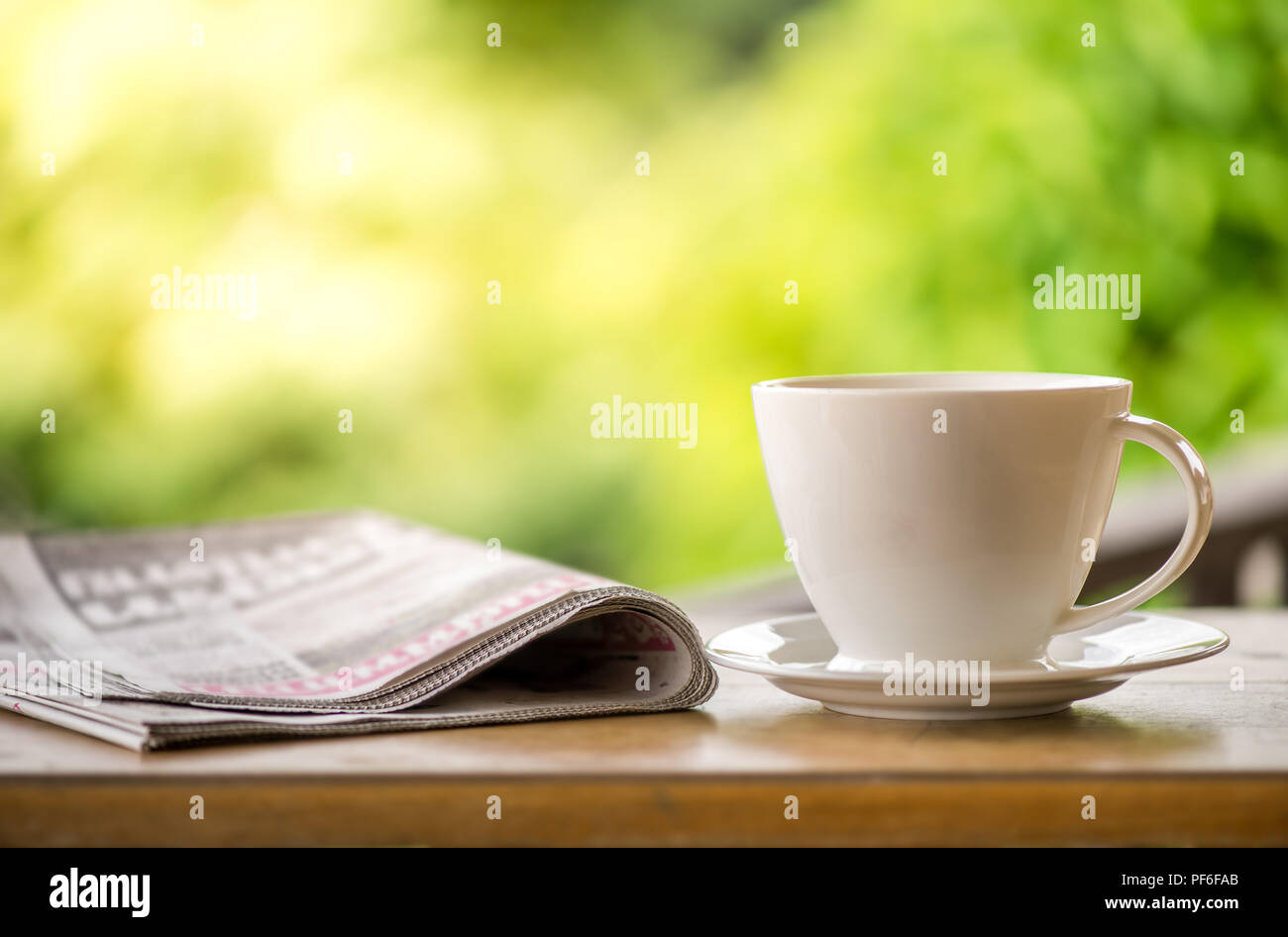 Guten Morgen Kaffee Tasse mit Nachrichten Papier auf die Natur grün Hintergrund im Garten Stockfoto