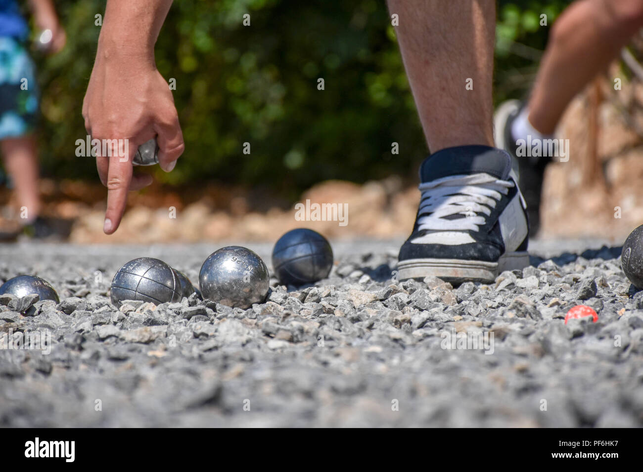 Petanque Spieler am Boden zeigt, halten eine Stahlkugel Stockfoto