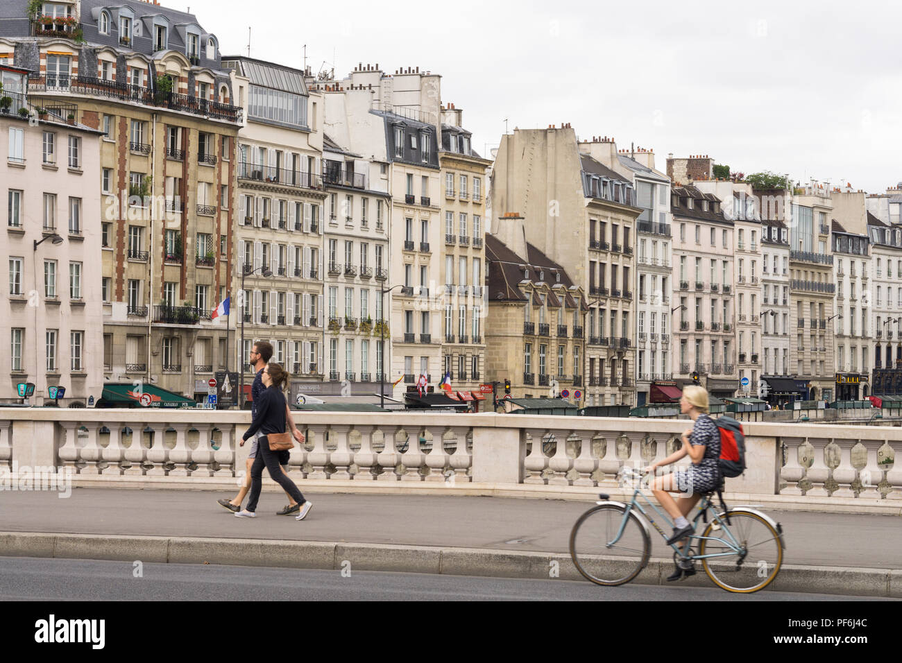Paris Stadtbild - Frau Radfahren über die Saint Michel Brücke, Gebäude am Quai des Grands Augustins sind im Hintergrund. Paris, Frankreich, Europa. Stockfoto
