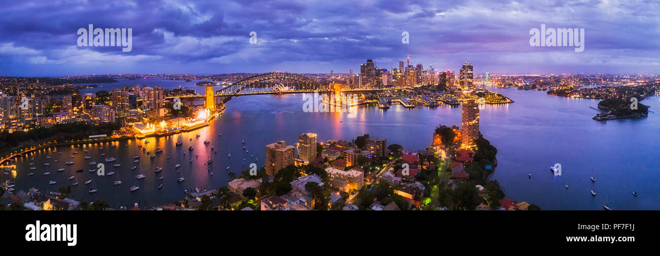 Dunkelblau Sonnenuntergang über die Stadt Sydney im Sydney Hafen Küsten von Nord nach Innenstadt durch die Harbour Bridge in erhöhten Antenne weiten Panoramablick verbunden. Stockfoto