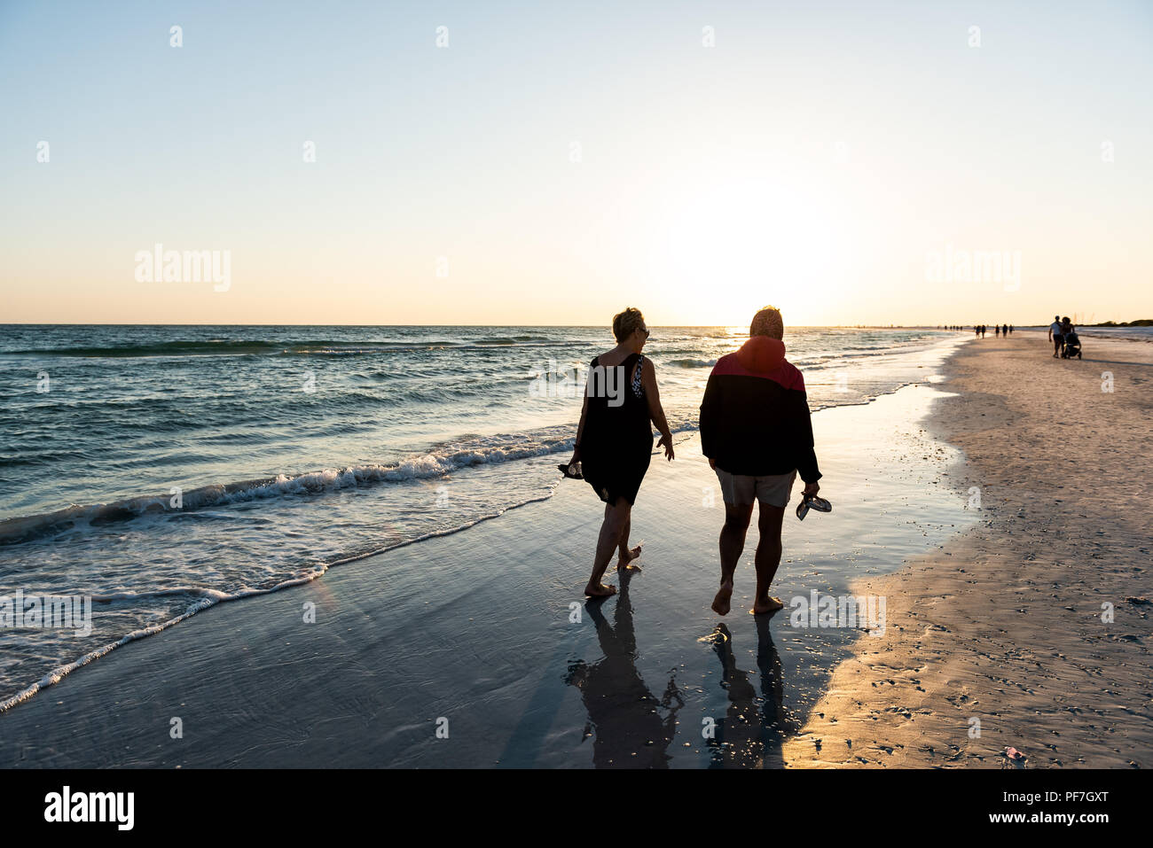 Sarasota, USA - 27. April 2018: Sonnenuntergang in Siesta Key, Florida mit Küste Küste Ozean Golf von Mexiko am Strand Ufer, viele Menschen silhouette laufen. Stockfoto