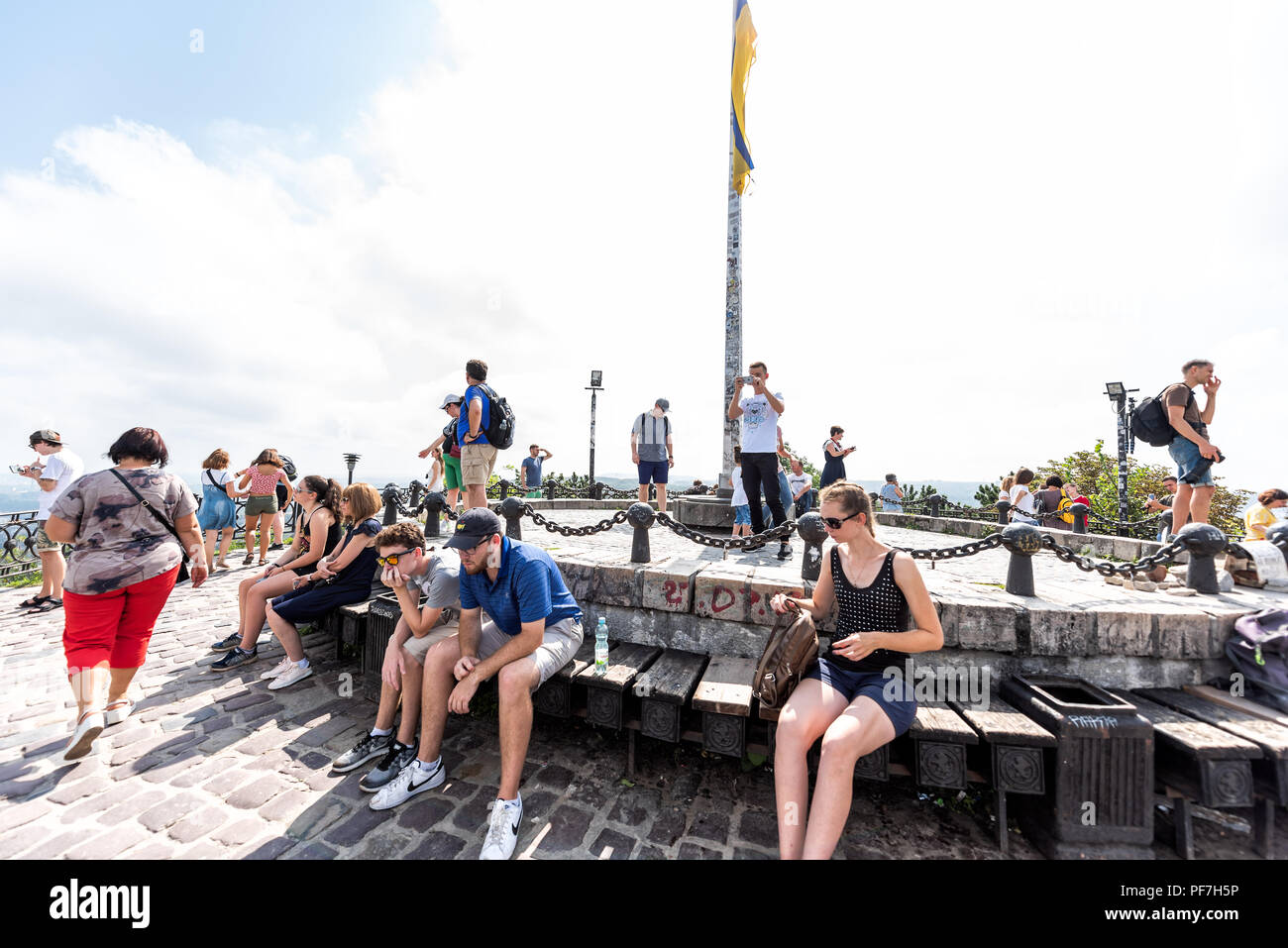Lemberg, Ukraine - August 1, 2018: Die Menschen sitzen an der Spitze der hohen Castle Hill ruhen, Ukrainisch Polnisch Altstadt Berg mit Fahne, sonnige s Stockfoto