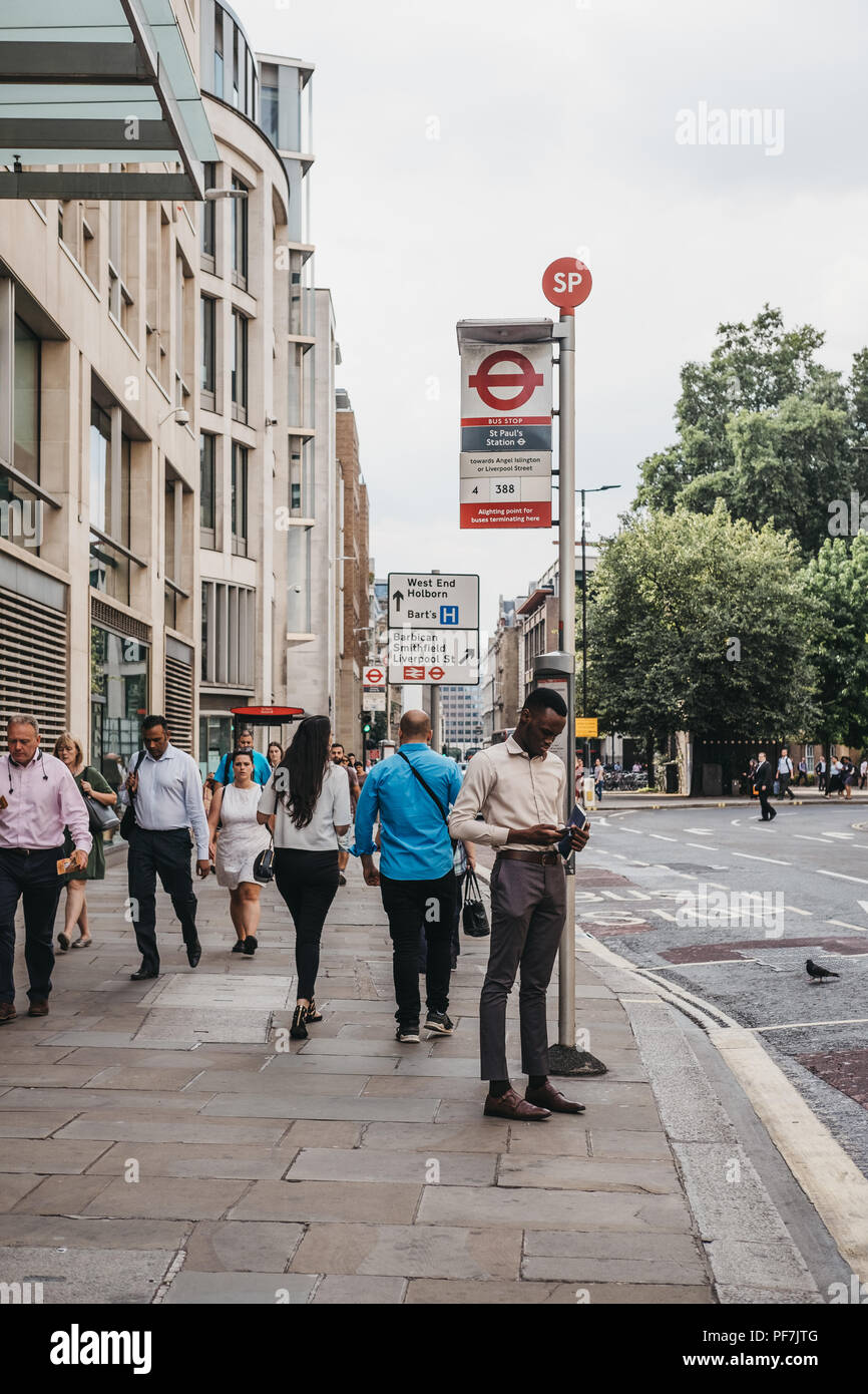 Mann sein Handy surfen beim Warten auf einen Bus auf dem Bus die St. Paul's Stop in der Stadt London, berühmten Londoner Financial District. Stockfoto