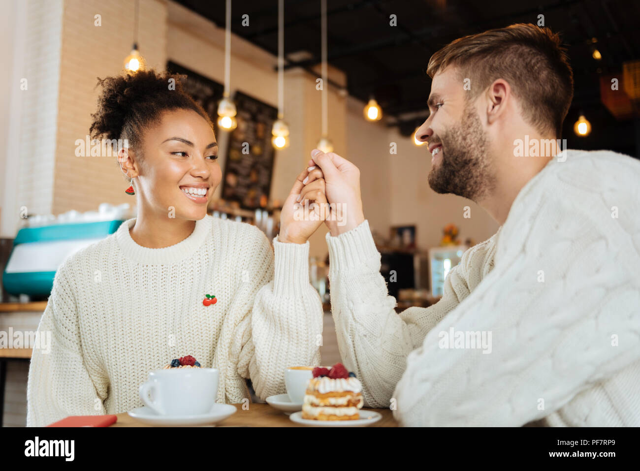 Curly dunkelhaarige Frau lächelnd die Hand ihres Mannes Stockfoto