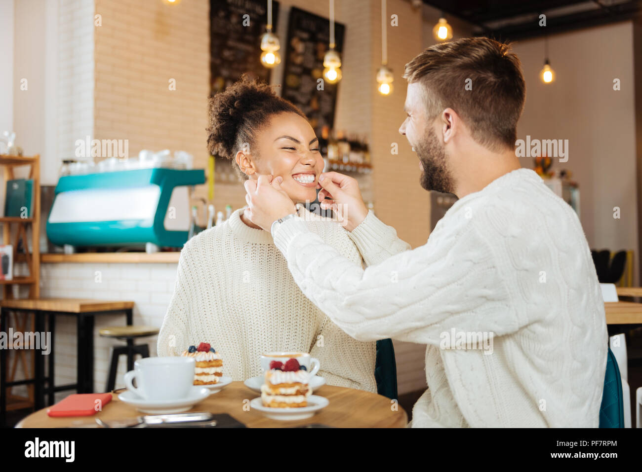 Nettes Paar tragen den gleichen Pullover essen leckere Desserts Stockfoto