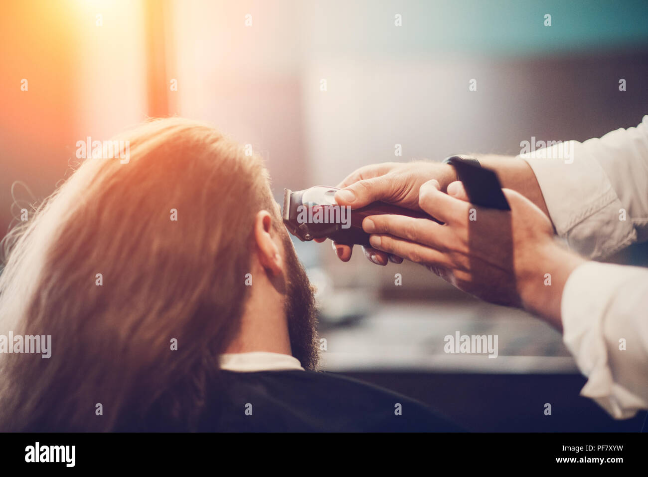 Friseur, Frisur. Bärtige Modell Mann und Friseur hand mit Rasierer und Trimmer Comb. Stockfoto