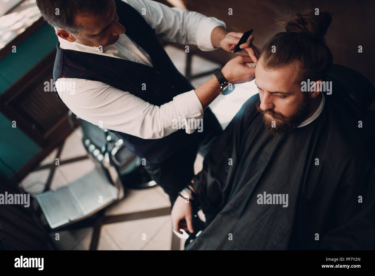 Barbershop mit Interieur aus Holz. Bärtige Modell Mann und Friseur. Stockfoto