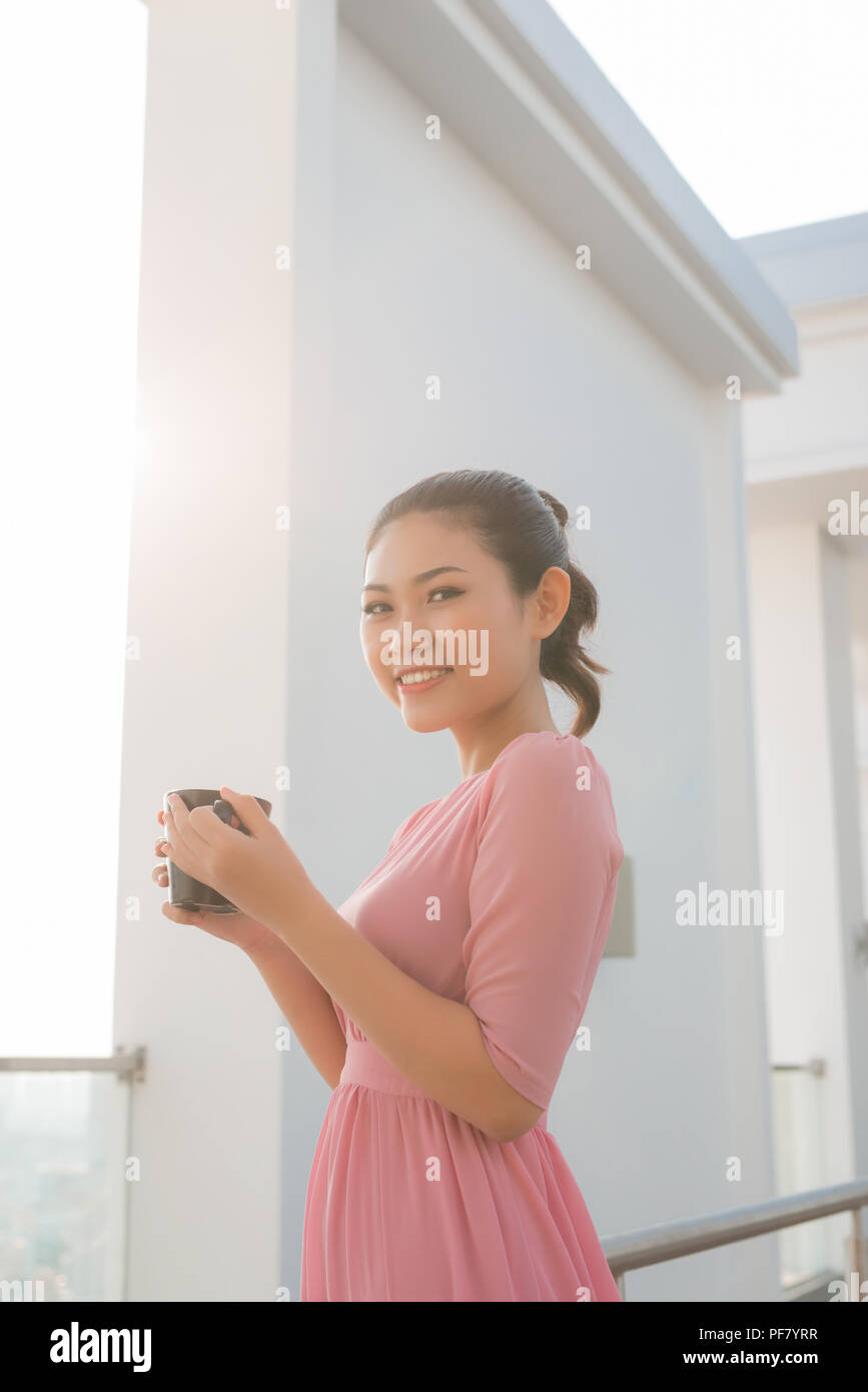 Junge Frau mit Kaffee Tasse Lächeln auf die Kamera schaut Stockfoto