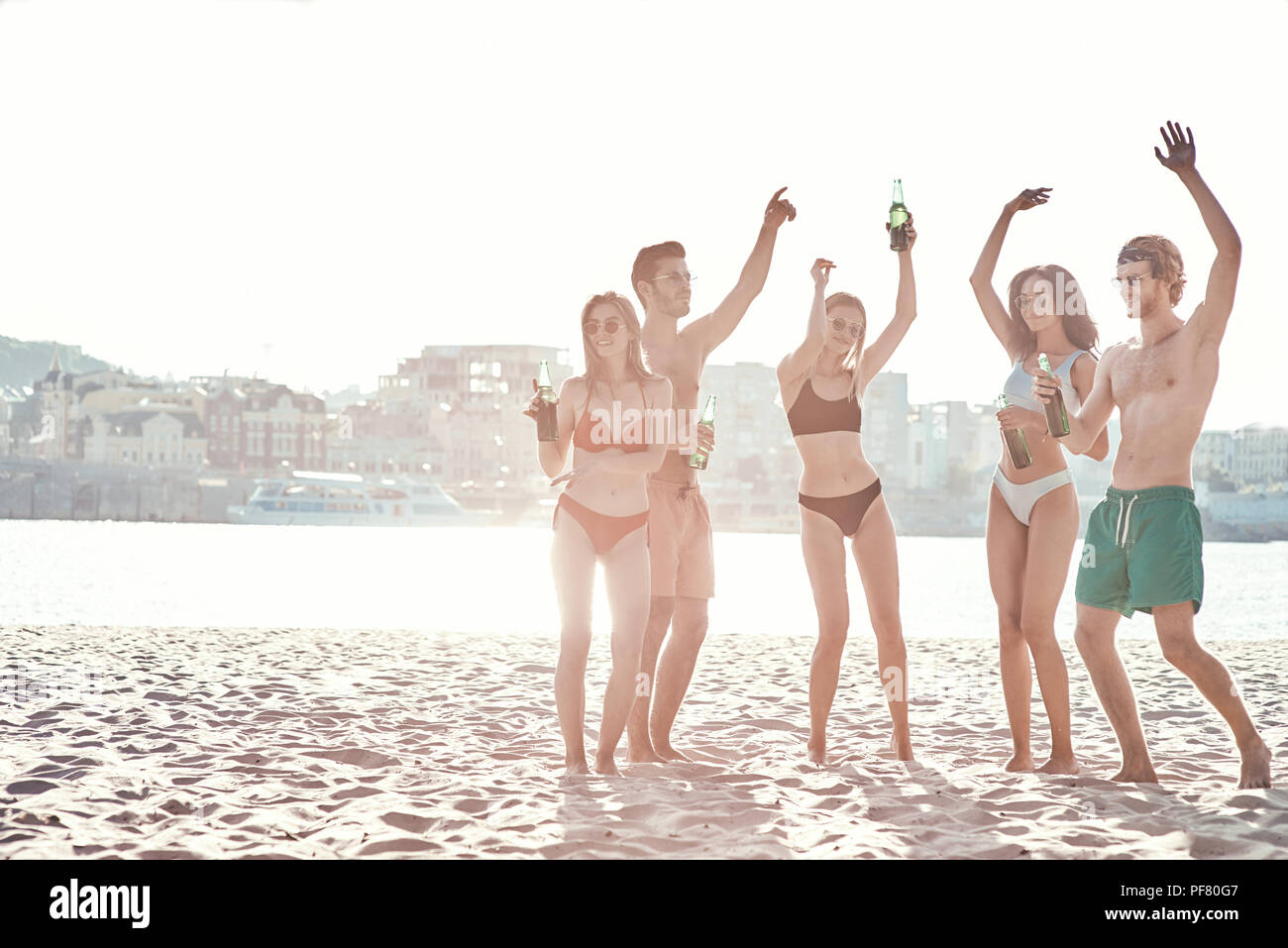 Genießen Sie unbeschwerte Zeit mit Freunden. Fröhlicher junger Menschen verbringen eine schöne Zeit zusammen, während am Strand zu sitzen und Bier trinken. Stockfoto