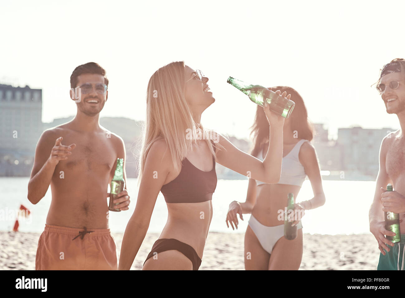 Genießen Sie unbeschwerte Zeit mit Freunden. Fröhlicher junger Menschen verbringen eine schöne Zeit zusammen, während am Strand zu sitzen und Bier trinken. Stockfoto