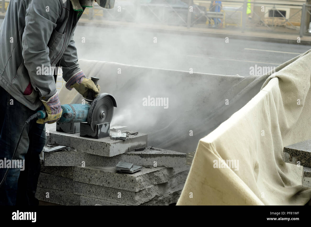 Der Arbeitnehmer Kürzungen ein großer Leistungsstarker Winkelschleifer Brammen ebnet. Stockfoto