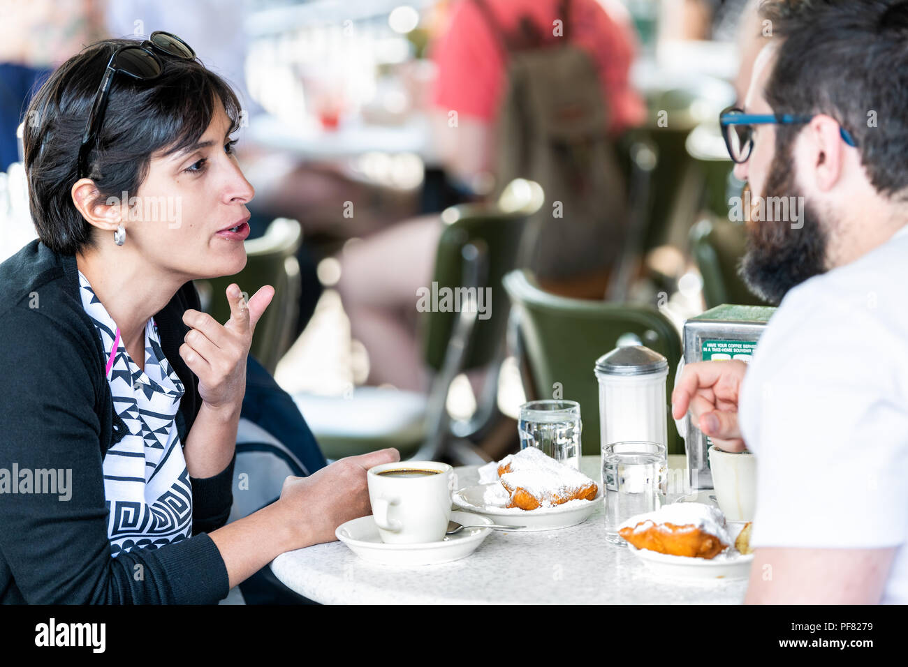 New Orleans, USA - 23. April 2018: Paar, Mann, Frau am Tisch an der berühmten kultigen Cafe Du Monde shop sitzen, trinken Kaffee, essen die Wegwarte beignet p Stockfoto