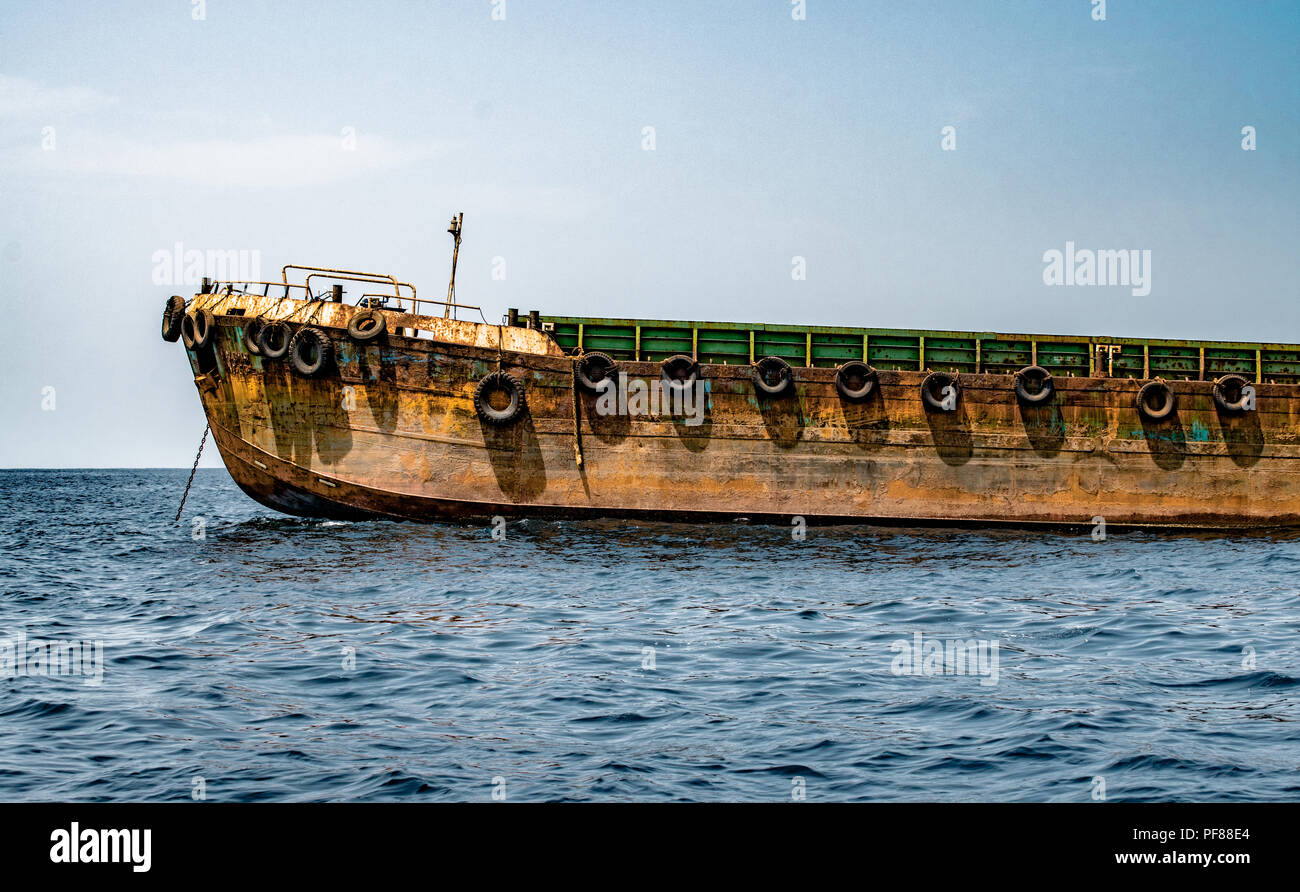 Schönes Bild von einem Verankerten Zubringer Schiff, Ladung in loser Schüttung ab Hafen der Stadt zum Mutterschiff am Anchorage verankert. Sieht ähnlich aus wie Stockfoto