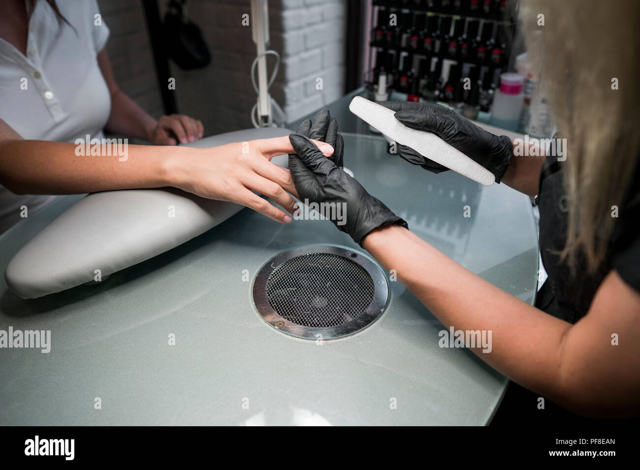 Kosmetikerin schleift das Nagelstudio für eine Maniküre im Schönheitssalon. Finger Nagelpflege, Schleifen und Polieren. Maniküre Hände Maniküre machen Frauen mit nagelknipser im Nagelstudio Stockfoto