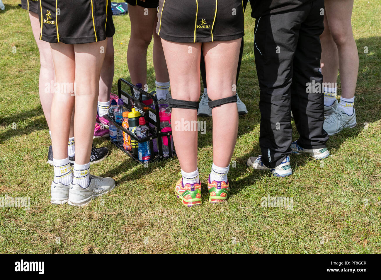 Die Hälfte der Zeit Team sprechen für eine Mädchenschule netball Team, den Trainer zu Ihnen spricht. Nur Beine und Turnschuhe sind sichtbar Stockfoto