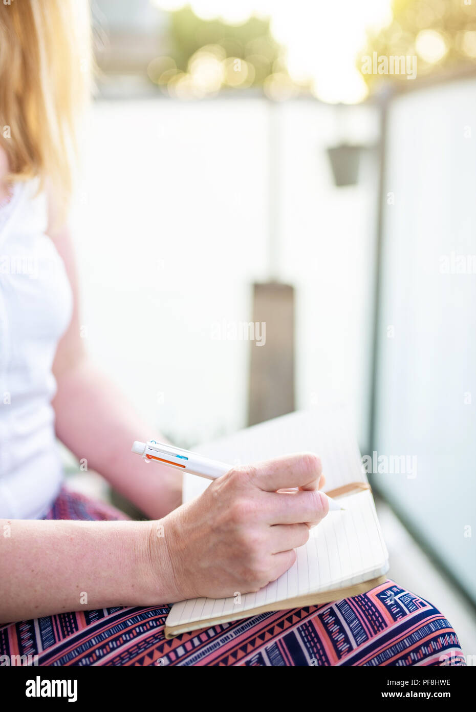 In der Nähe von Frau sitzt auf der Terrasse Notizen im Notebook Stockfoto