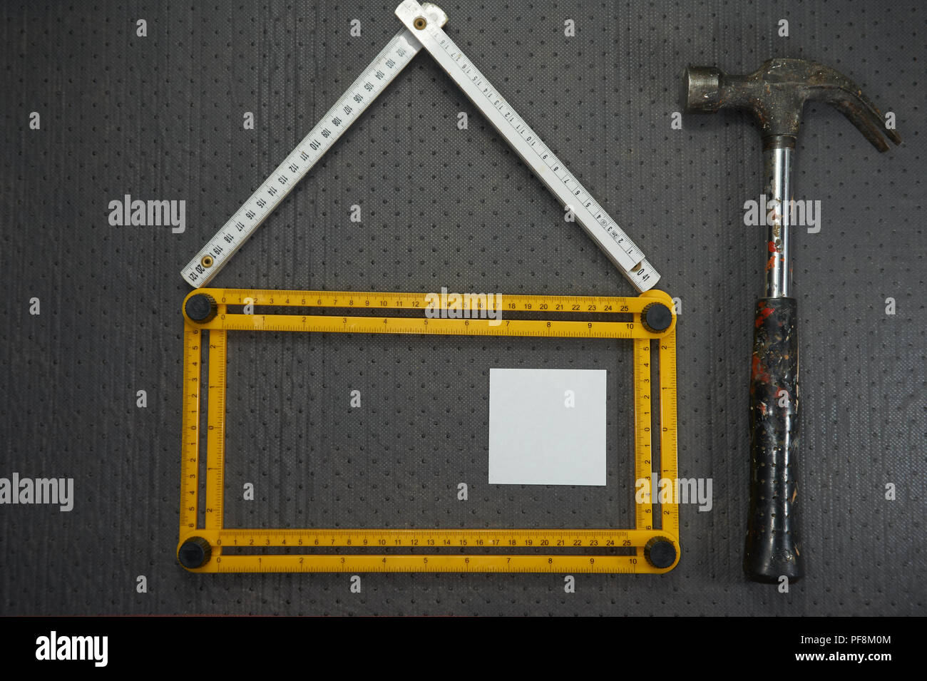 Konzeptionelle Bau- und Renovierungsarbeiten noch Leben mit einem Flach Design eines Hauses durch einen gelben und weißen Herrscher, Hammer und leere Haftnotizen gebildet Stockfoto