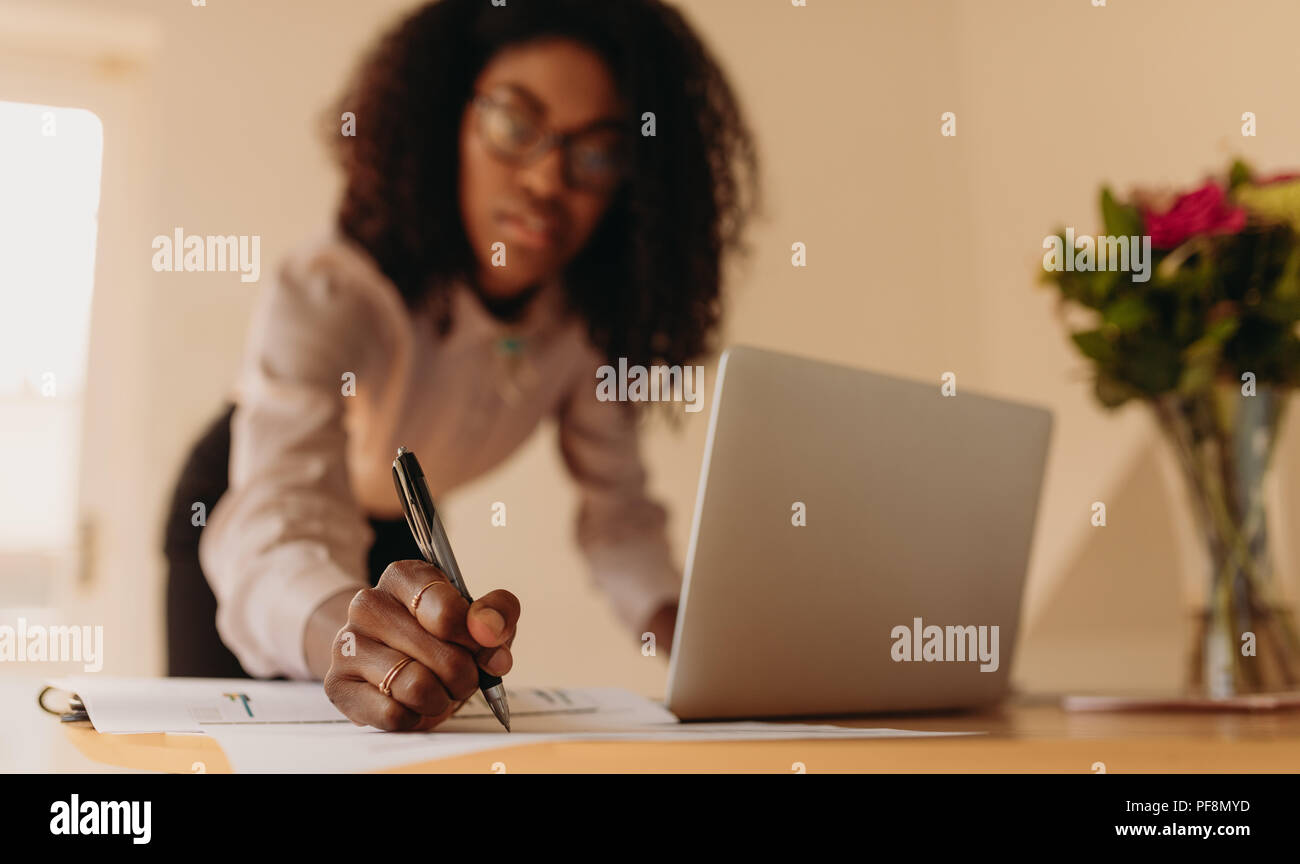 Nahaufnahme der Hand einer Frau Unternehmer lehnte sich über den Tisch Notizen zu schreiben, während am Notebook suchen. Geschäftsfrau Notizen suchen In einem la Stockfoto