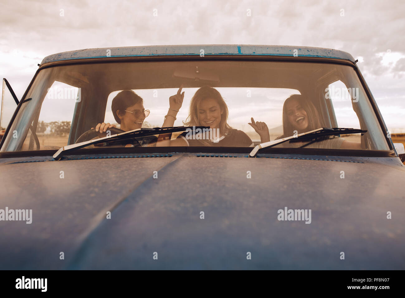 Gruppe von Menschen, die in einem Lkw, Spaß zu haben. Junge Frauen mit auf eine Reise in die Landschaft. Stockfoto