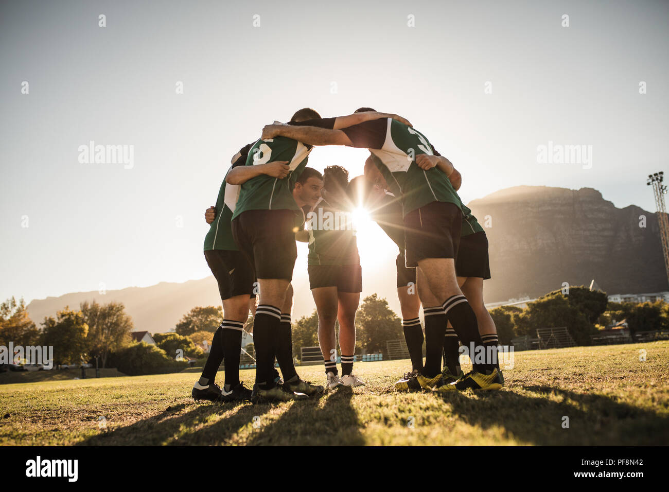 rugbyspieler stehen im Kreis mit den Händen auf den Schultern. Das rugby-Team ist nach dem Spiel in der Nähe. Strahlender Sonnenschein durch die Gemütlichkeit. Stockfoto