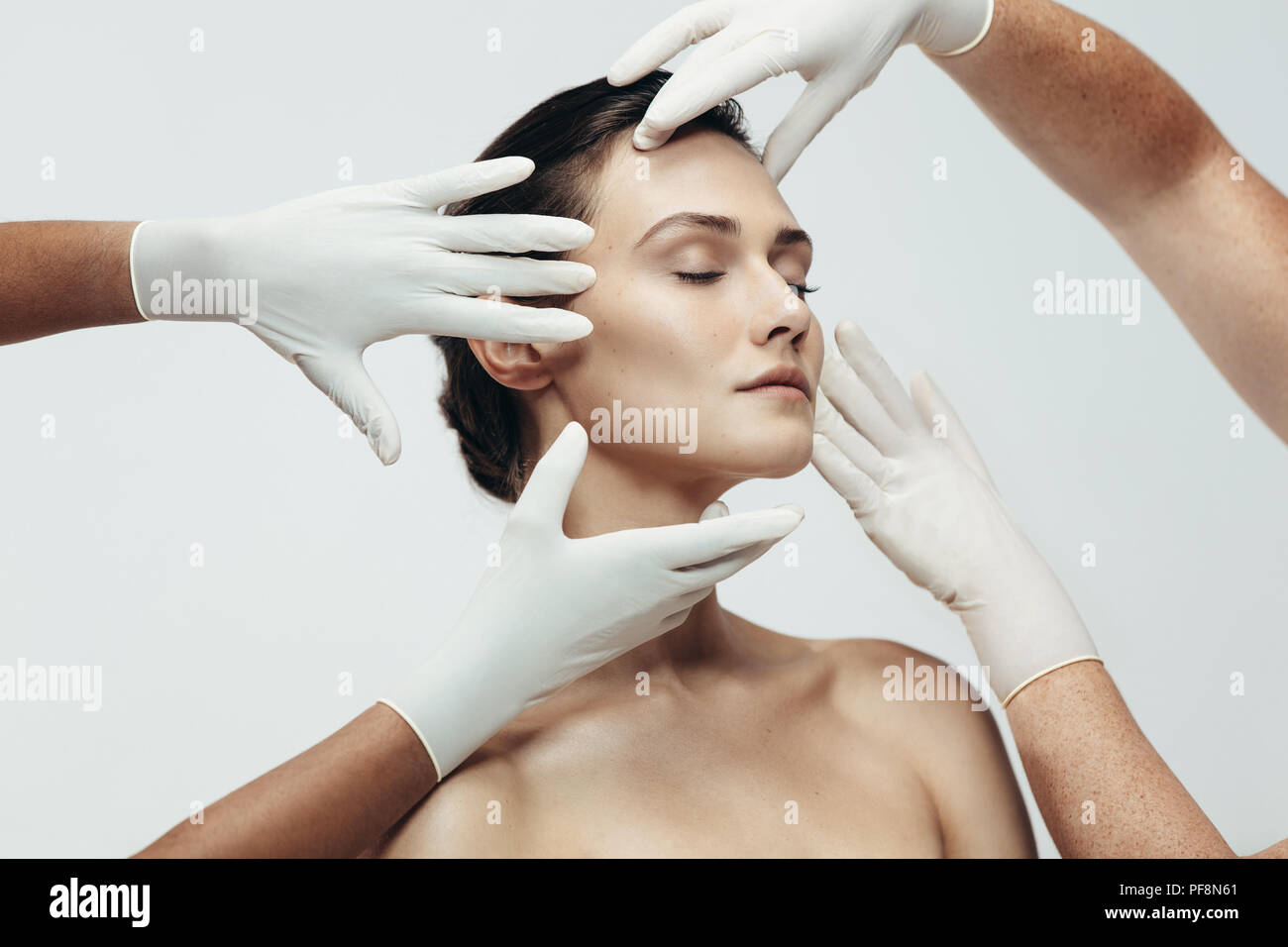 Zwei cosmetologists berühren und Prüfung der Gesichtshaut einer Frau. Frau Gesicht Kosmetikerinnen Hände in Studio geprüft wird. Stockfoto
