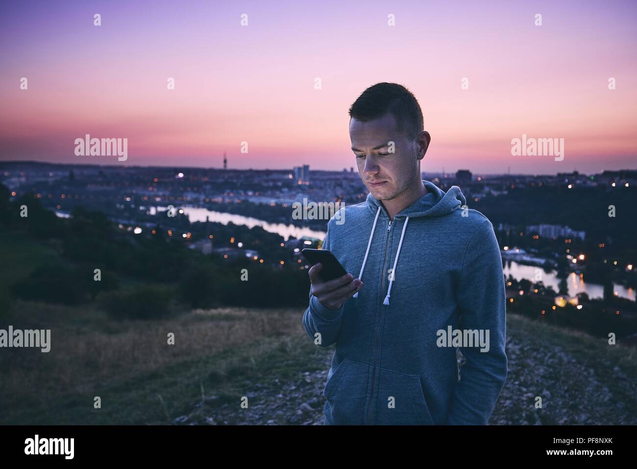 Einsamkeit schöner Mann mit Handy gegen Städtischen Skyline bei Sonnenaufgang. Stockfoto