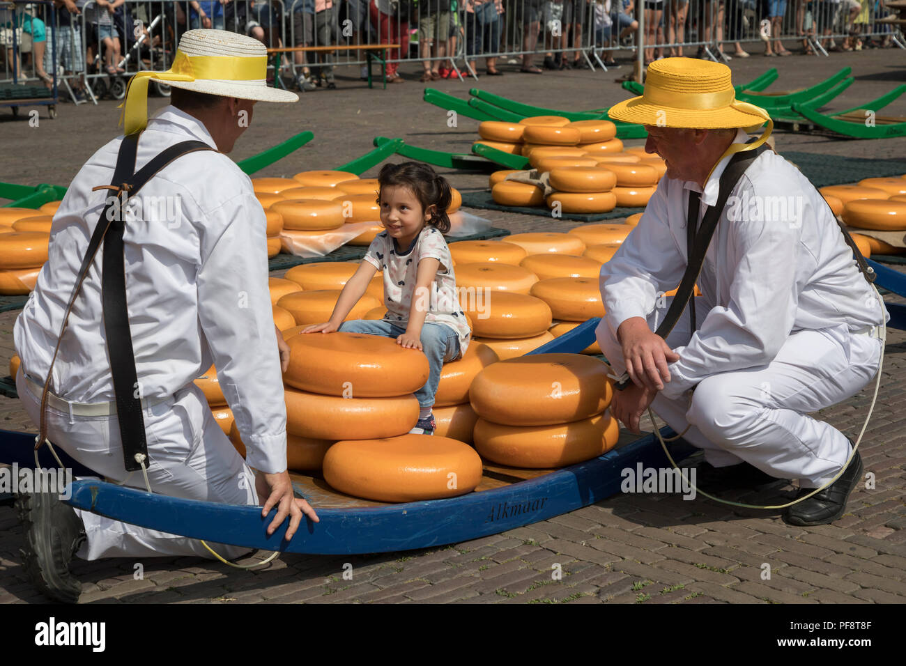 Alkmaar, Niederlande - 20 Juli 2018: Traditionelle Käse Träger im Gespräch mit einem kleinen Mädchen sitzen auf ihren Käse Stretcher Stockfoto