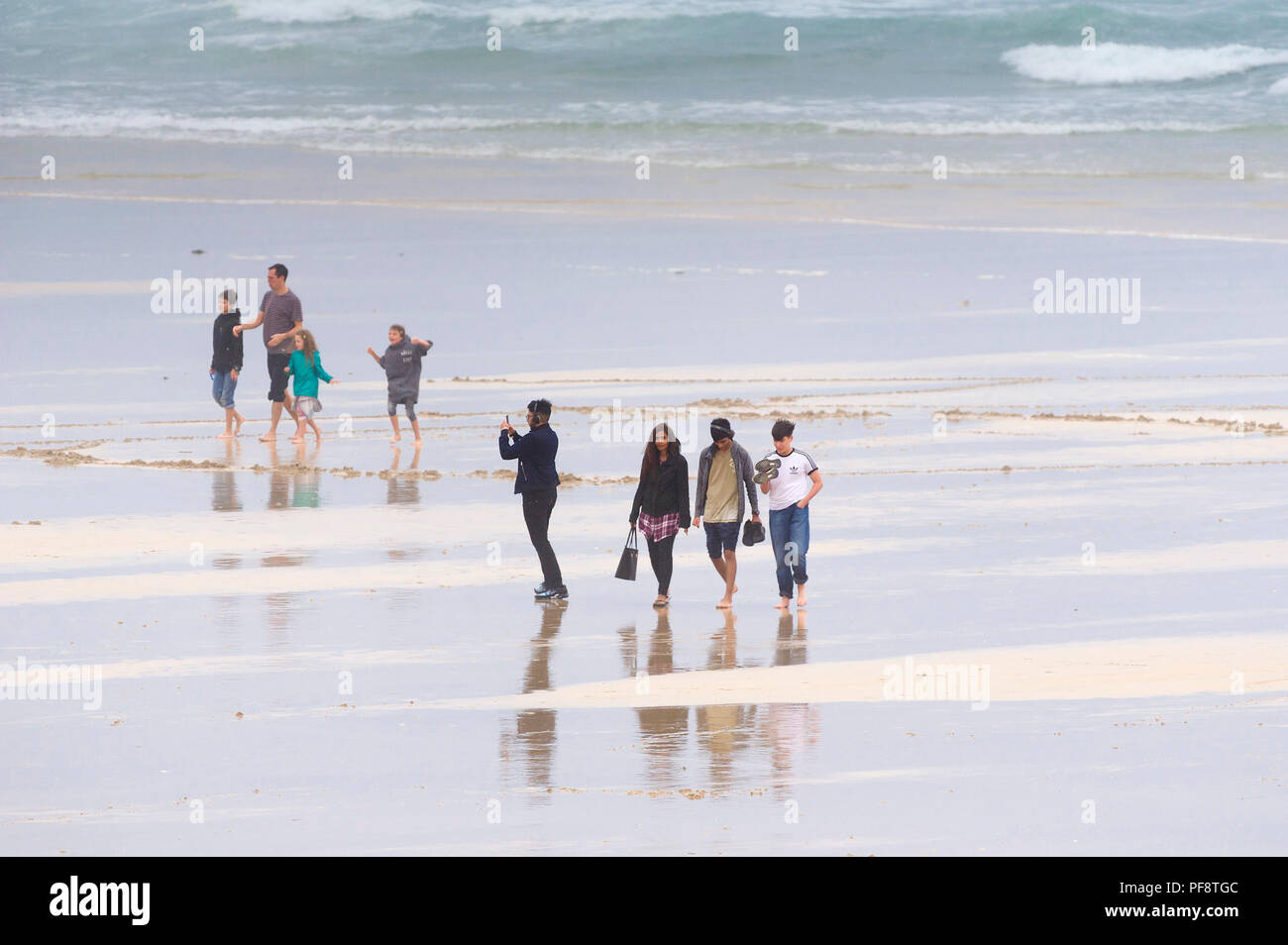 Urlauber zu Fuß auf den Fistral Beach auf einem nebligen kalten Tag. Stockfoto