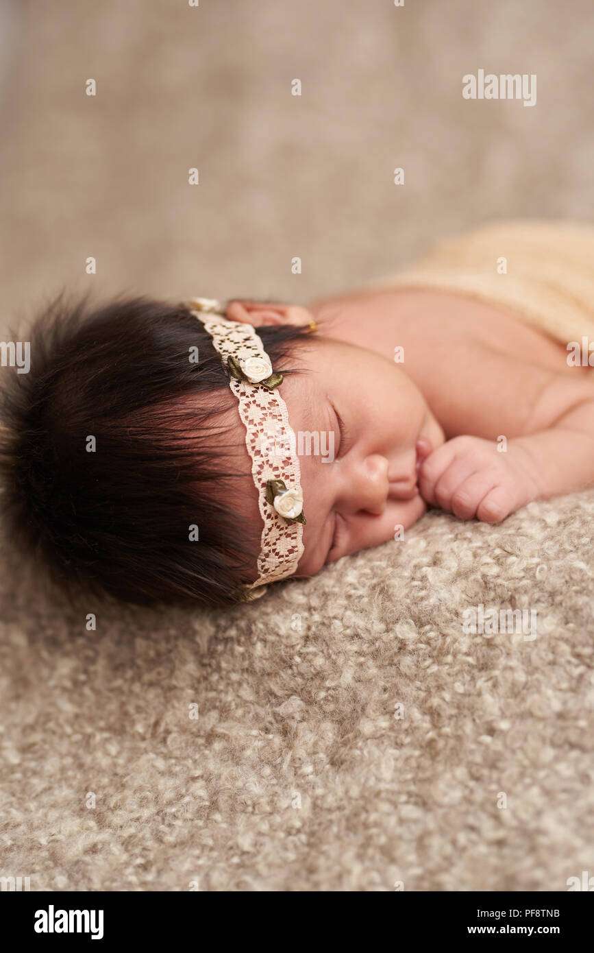 Neugeborene schlafen und saugen Hand auf braunem weichem Hintergrund Stockfoto